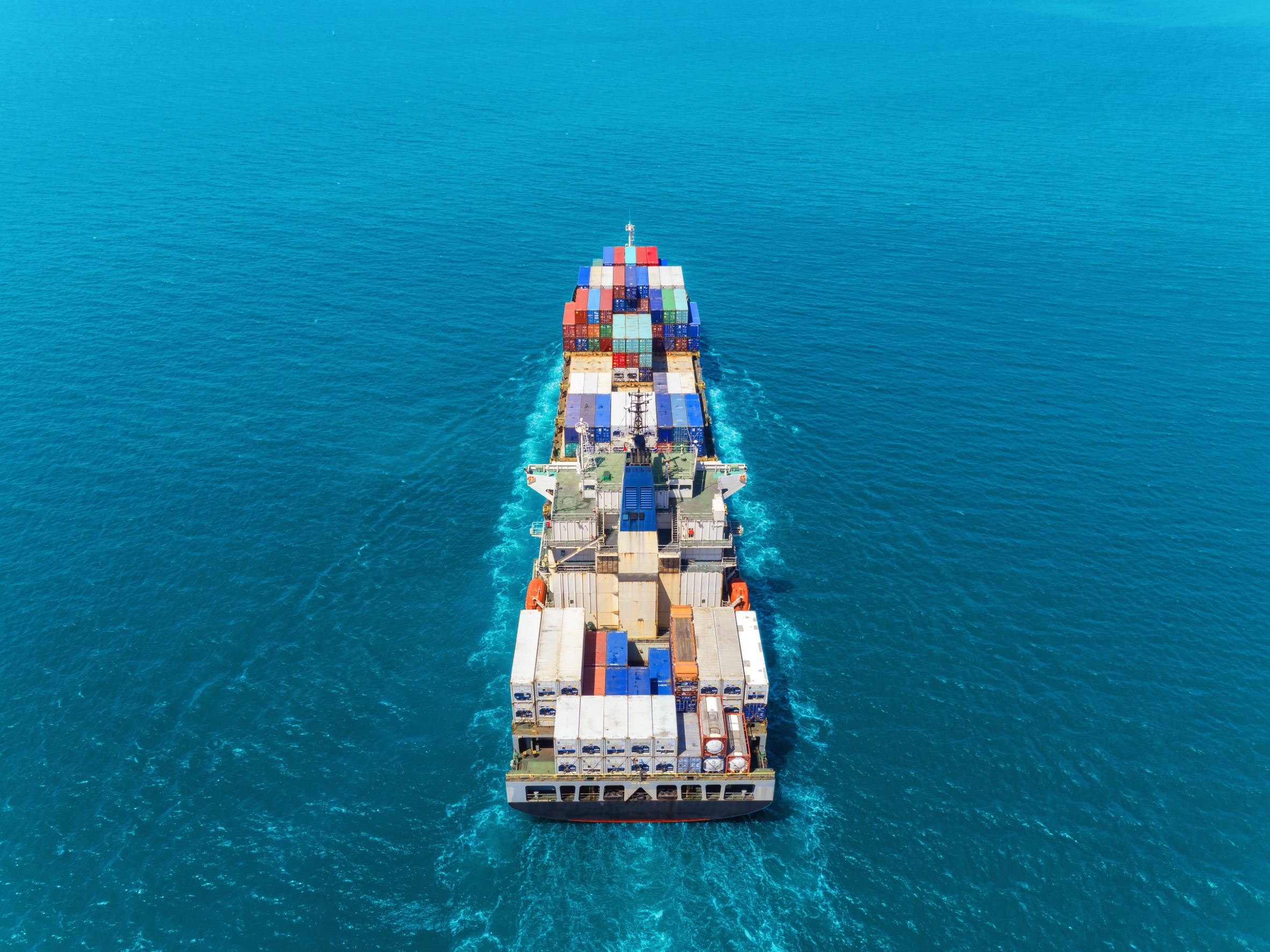 Qemi International A Cargo ship loaded with containers for international transfer solutions.